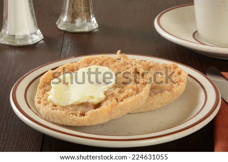A toasted and buttered whole grain English muffin with a cup of coffee