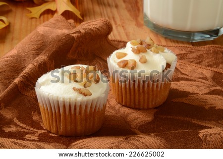 Small carrot cake cupcakes with frosting and a glass of milk