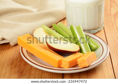 A healthy snack with celery sticks, apple slices and cheese
