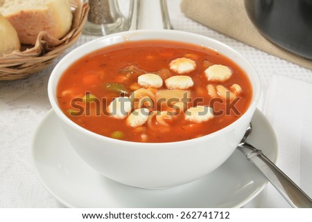 A bowl of vegetable beef soup with dinner rolls