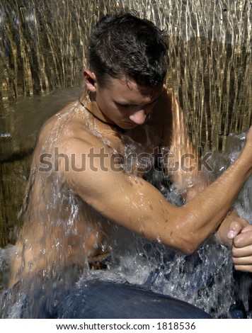 Young man cooling off under a waterfall