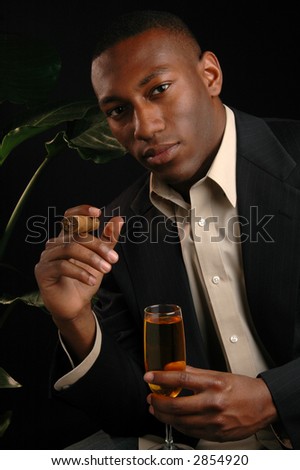 A handsome man in a cigar bar with a glass of champagne