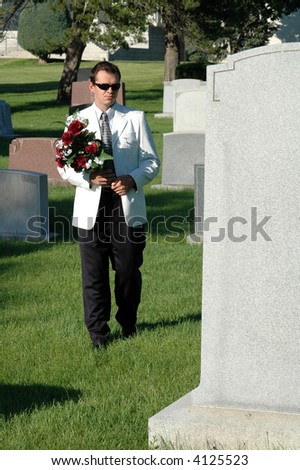 A man with a bouquet of flowers walking through a cemetery