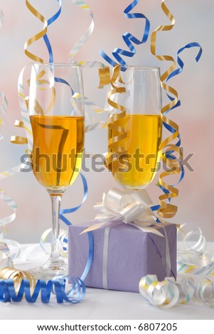 Party ribbon falls around champagne glasses and a gift