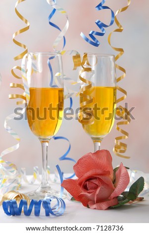 Party ribbon falls on top of glasses of champagne and a rose