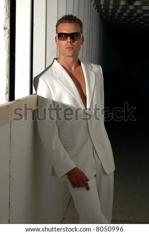 A sophisticated man in white leans against a construction walkway