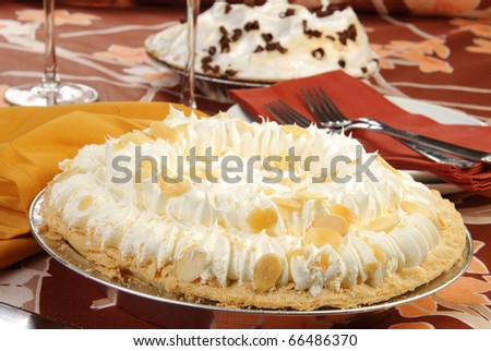 A banana cream pie with a chocolate meringue pie in the background