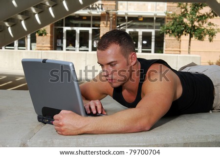 A college student outside the school working on a laptop computer