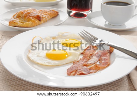 Bacon and eggs with a Danish pastry, grape juice and coffee
