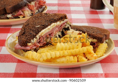 A corned beef sandwich with fries on a picnic table