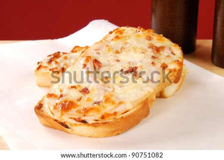 An open faced panina sandwich with melted cheese on waxed paper