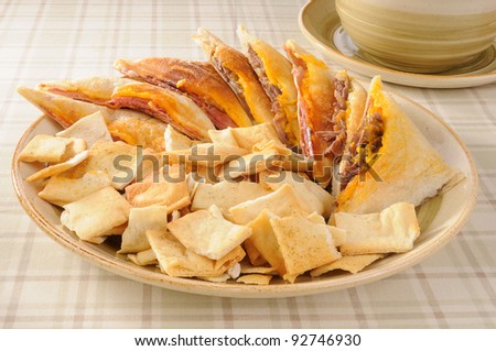 A party tray with beef and ham paninis with toasted pita chips