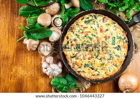 Frittata made of eggs, mushrooms and spinach on a frying pan. Italian cuisine. Top view Foto d'archivio © 