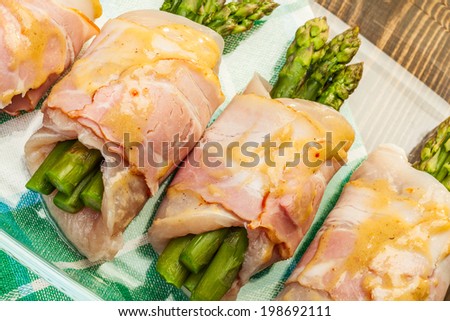 Fresh asparagus wrapped in chicken and bacon in a baking dish