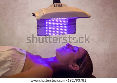 a woman under a light therapy machine, blue light