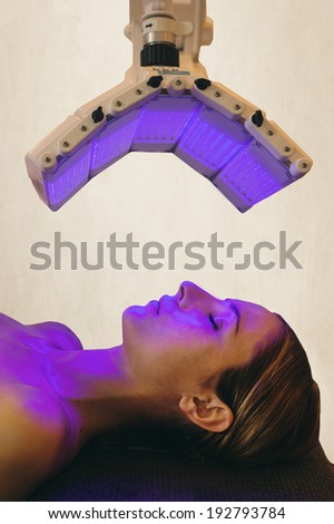 a woman under a light therapy machine, blue light