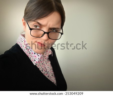 Displeased unsure arguable suspicious thinking young beautiful lady in glasses frowning wondering uncertain gaze with hostility mistrust on grey background. Negative face expression emotion perception
