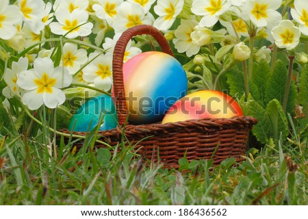 Easter eggs in a easter basket, with flowers in a meadow