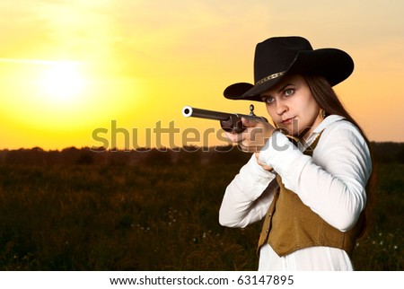 Cowboy woman with a gun in a sunset time.