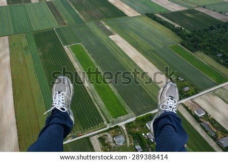 Man paragliding above  fields of crops