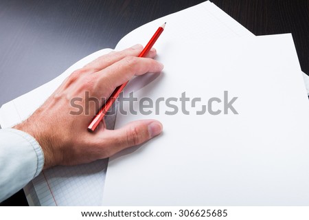 Man takes notes in pencil on paper.