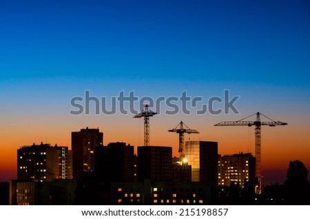 high buildings under construction with cranes and illumination at night