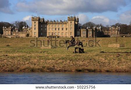 A horse rider jumping in front of Floors Castle Kelso Scotland