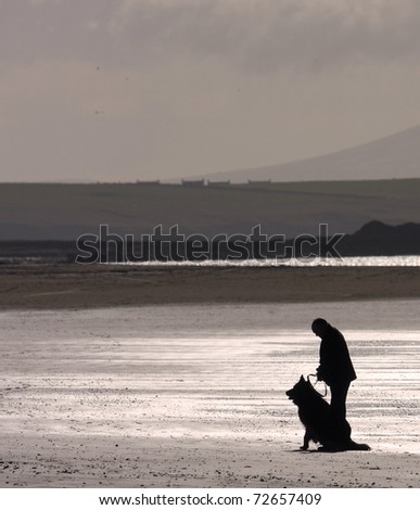 Dog walker on the Cymyran beach on the Isle of Anglesey North Wales