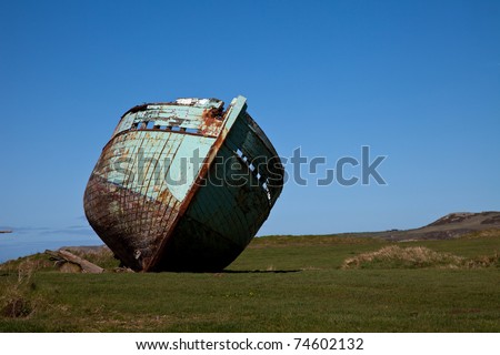 Old boat beached on a field on the coastal path Isle Anglesey North wales