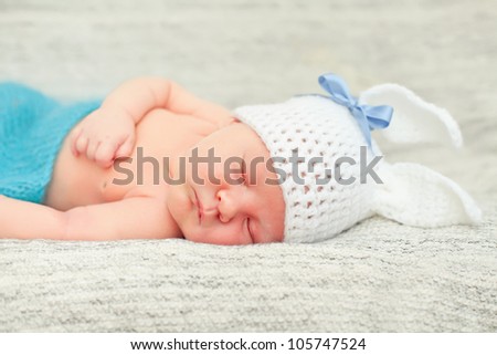 Funny sleeping newborn child. Bunny cap on head of boy. Newborn baby boy a sleep on a blanket. Soft focus, shallow DoF.