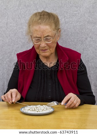 Sad old woman looking at her medicine meal