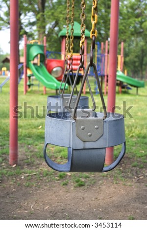 Empty swing set in a park on a sunny day. Shallow depth of field focus on the first swing.