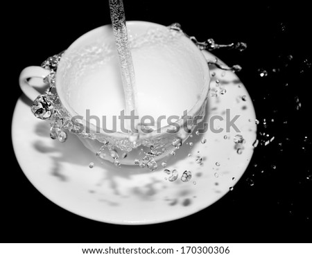 water in the cup with splashes on a black background
