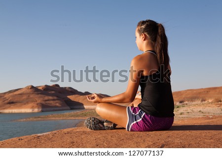 Young woman doing yoga at the shore of Lake Powell in the southwestern US desert.
