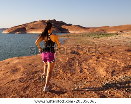 Young woman having a morning work out and run along the shore of Lake Powell in the southwestern US desert.