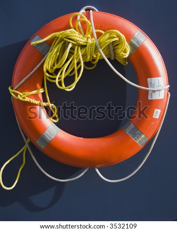 Orange life preserver ring with a rope on a blue background in the sun