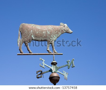 Old style weather vane with a cow figure used to indicate wind direction