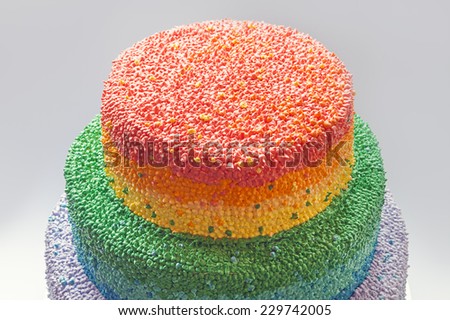 Details of a birthday cake decorated with cream in rainbow colors.