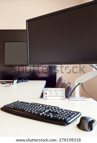 Interior of a modern office, furniture in white and computer hardware on table.