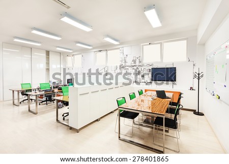 Office interior in white with printed wallpapers presenting part of a machine structure.