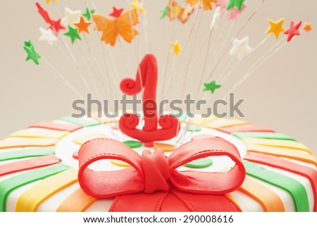 Sugar red ribbon on first year birthday cake, details of decoration.