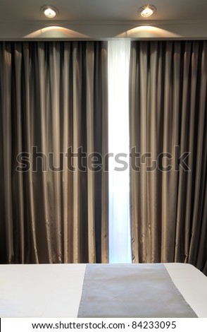 Part of a hotel room, just a bed and curtain with two lights.