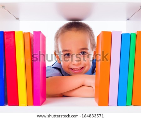 Little boy standing behind shelf with colorful books