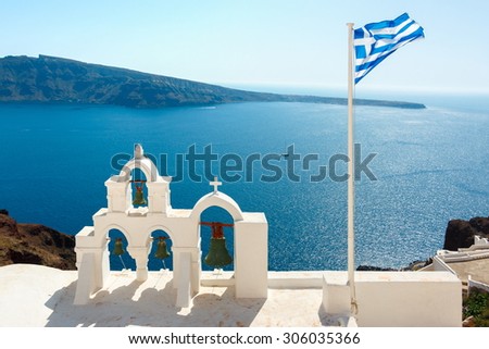 Bell towers and Greek flag in Oia town, Santorini island, Greece