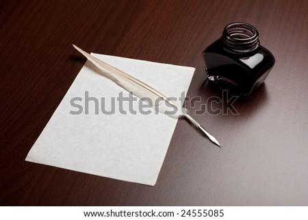Ink, quill and an empty page on brown desk