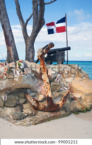 old cast-iron cannon, and the ship anchor in front of of the flag of the Dominican Republic on the Atlantic coast