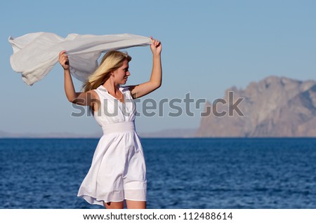 Girl waving a white handkerchief in the wind at the sea