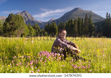 Guy sitting in the mountains on a meadow. Morning landscape. Slovakia.