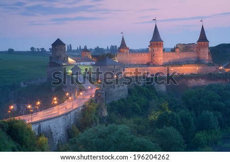 Night landscape with a road leading to the old fortress. Illumination on a historic building. Historic Landmark. Old town of Kamenetz-Podolsk, Ukraine, Europe