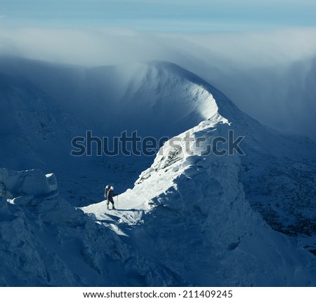 Winter landscape. Sunny day in the mountains. Tourist standing on a rock
